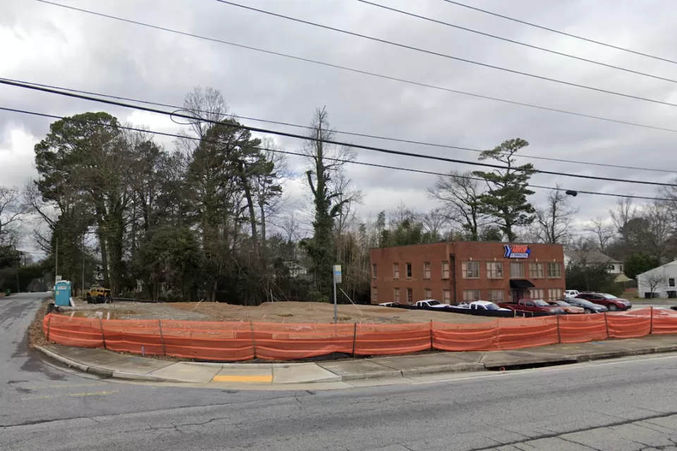 Vacant corner lot in Atlanta, Georgia surrounded with low orange plastic construction fencing.